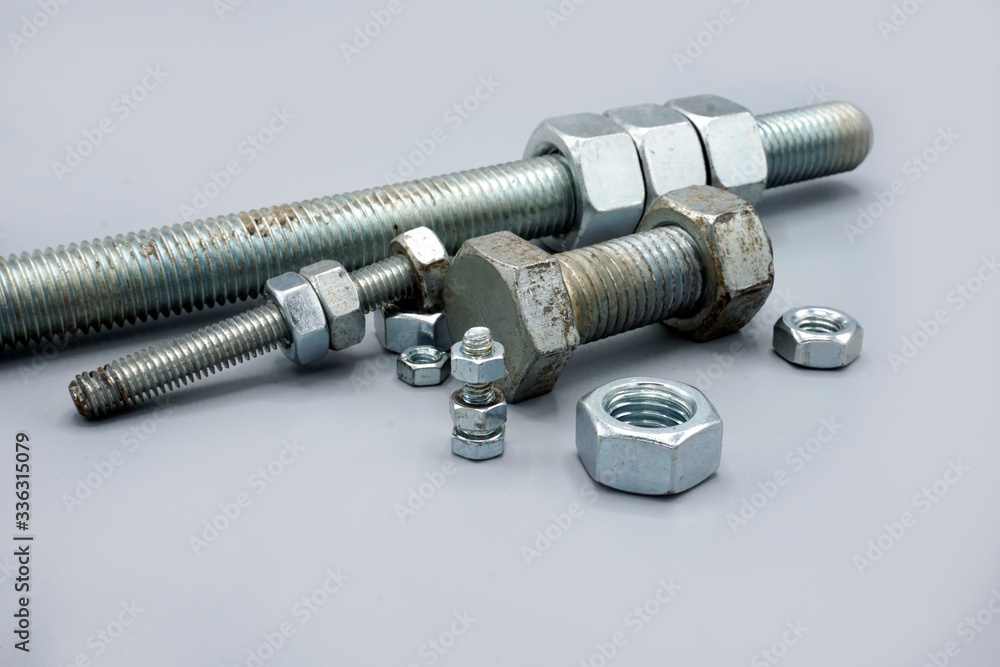 Metal screws and nuts isolated on gray background. New and shiny chrome screws and nuts. Copy space. Metal screws and nuts isolated on gray background. New and shiny chrome screws and nuts. Copy space.