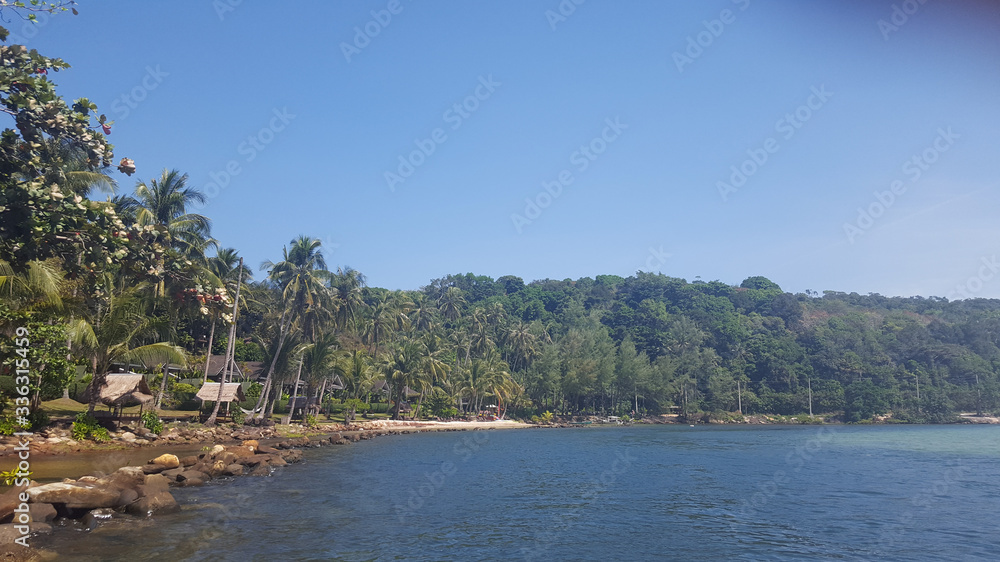 The photo was taken from a motor boat. View of the island, palm trees, ocean, spray, beach