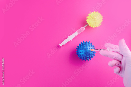 The hand in the gloves holds a syringe and injects the virus. Content for coronavirus on a pink background.