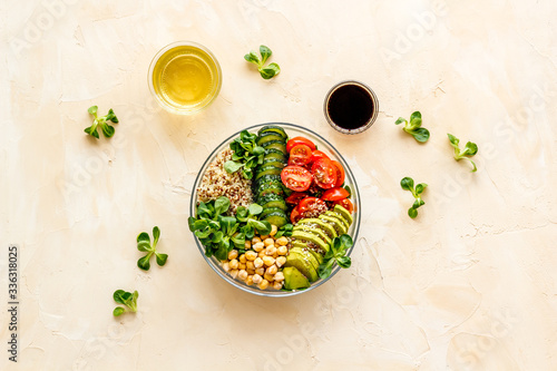 Veggie bowl. Vegetable salad with quinoa, avocado, tomato, spinach and chickpeas - on beige table. Top view