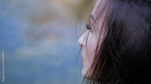 Closeup side portrait of beautiful brunette girl standing near river.