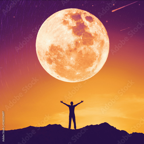 Man raise hand up on top of mountain with sunset sky and full moon star abstract background. Copy space freedom travel adventure and feel good concept.