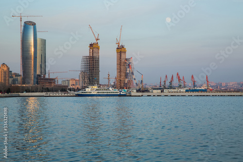 Baku, Azerbaijan - 3.02.2018: Baky skyline view from Baku boulevard the Caspian Sea embankment . Tall buildings in Baku. Ship cranes . Moon. harbor . Port