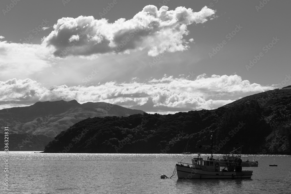 Fishing boats on the sparkling waters of a bay. Black and white. Taken at Akaroa Harbour, New Zealand