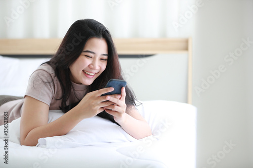 Woman using telephone on bed in bedroom.