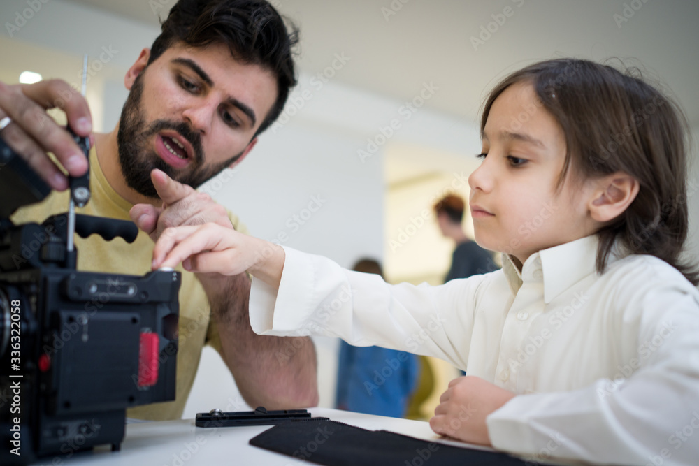Dad and son at home sitting and fixing camera Dad and son at home sitting and fixing camera