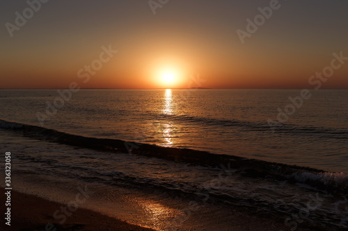 Sea coast at sunset, with the sun, wave, orange sky