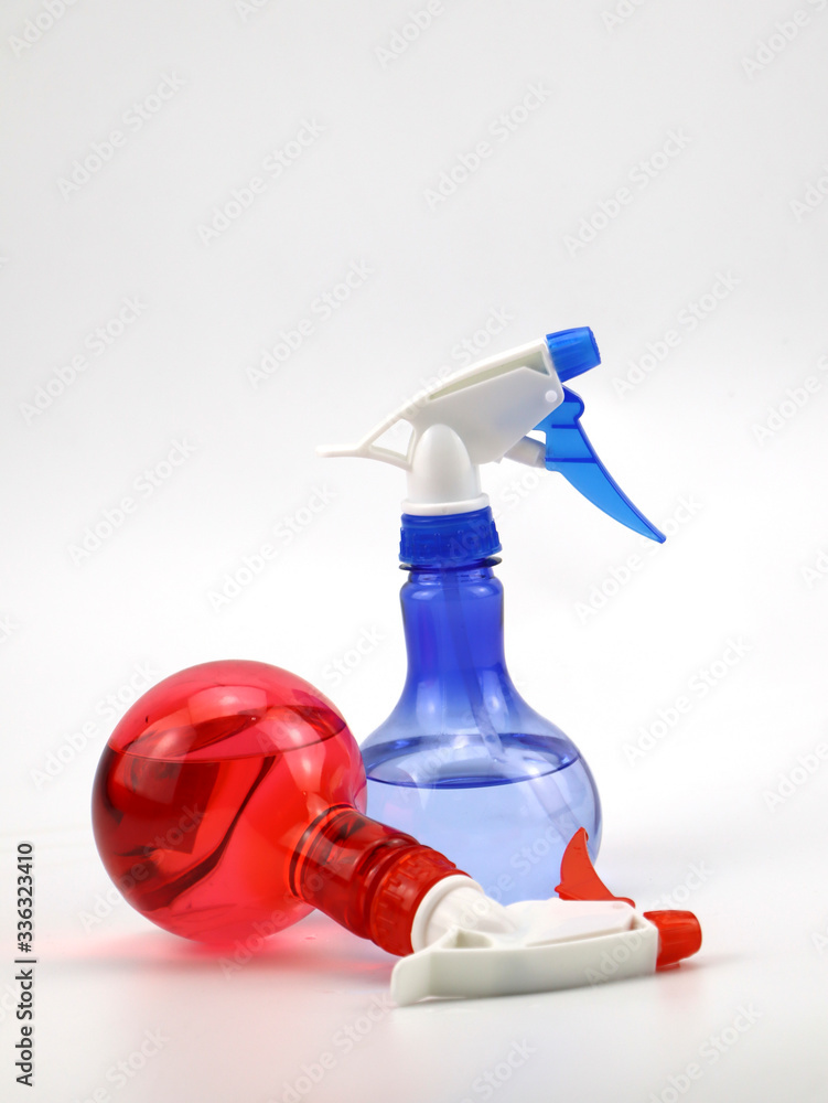 Two red and blue spray bottles are placed horizontally and vertically isolate on a white background. Two red and blue spray bottles are placed horizontally and vertically isolate on a white background.