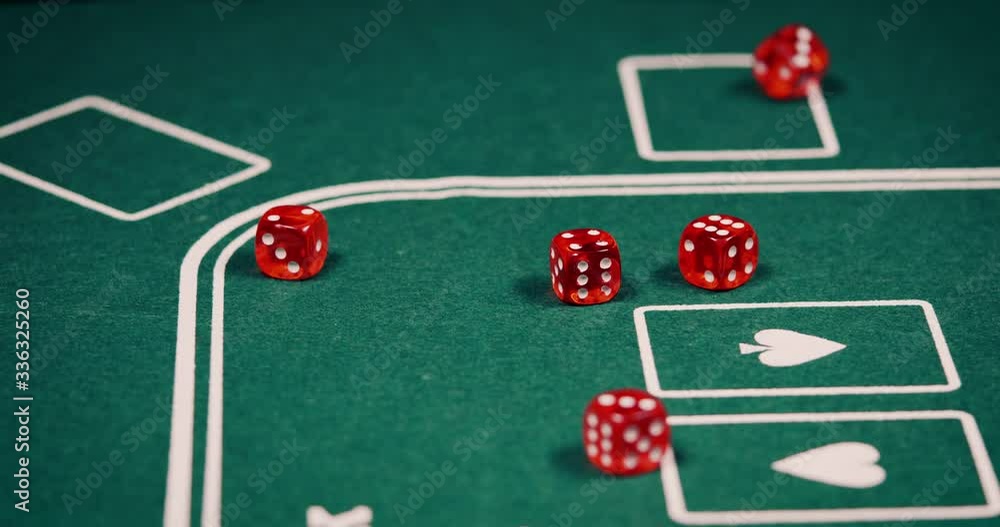 Close up of rolling dice in red on green poker table shot in 4k super slowmotion Close up of rolling dice in red on green poker table shot in 4k super slowmotion