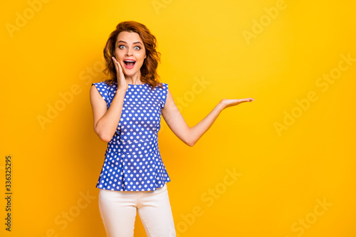 Portrait of nice attractive lovely amazed stunned glad cheerful cheery wavy-haired girl holding on palm cool solution present gift isolated on bright vivid shine vibrant yellow color background