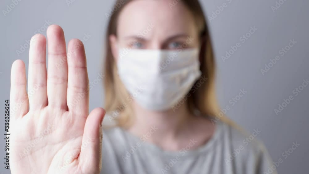 Help stop spreading globally corona virus pandemic infectious disease outbreak. On background woman in mask focus on stretched hand as symbol of keep distance avoid communication, healthcare concept Help stop spreading globally corona virus pandemic infectious disease outbreak. On background woman in mask focus on stretched hand as symbol of keep distance avoid communication, healthcare concept