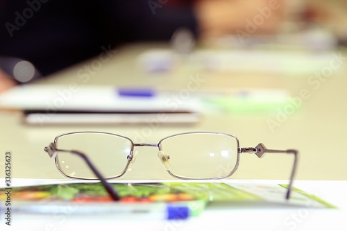 Backlit images of glasses on the desk selective focus and shallow depth of field . Glasses on the table with the engineer's office. glasses on office desk and office supplies.