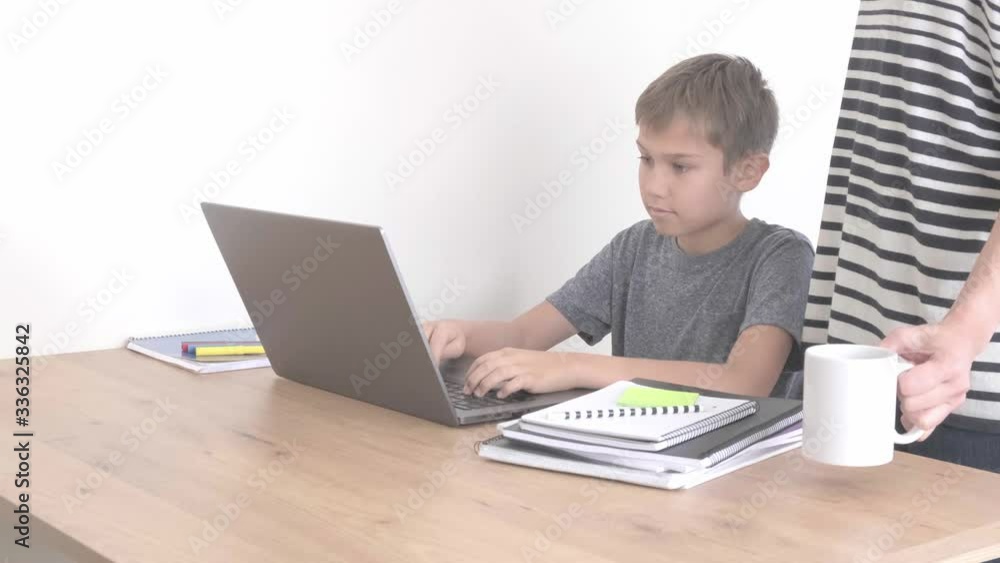 Child learning with laptop computer, doing homework at home. Mother come to help him. Technology, distance education, online learning from home Child learning with laptop computer, doing homework at home. Mother come to help him. Technology, distance education, online learning from home
