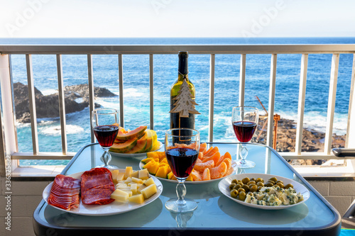 Canvas Print Red wine and Mediterranean dishes and tropical fruits on the Atlantic Ocean terr