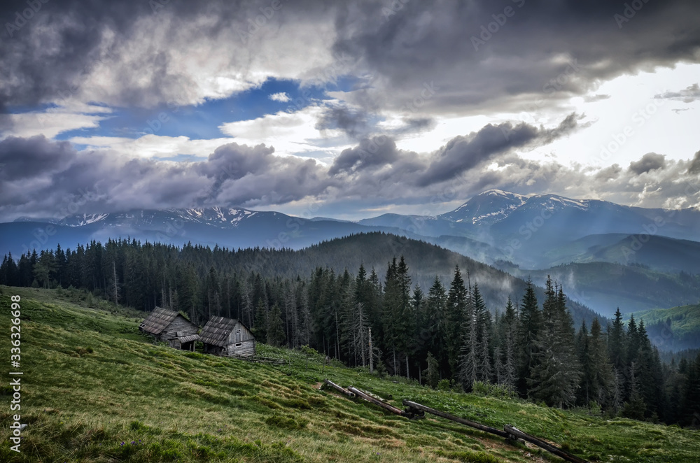 Old house in the Carpathian Mountains, the highest peaks of Ukraine in the background