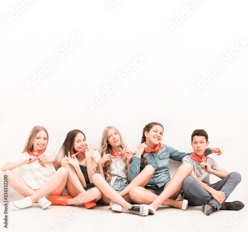 cute smiling tenagers sitting on the floor with legs crossed
