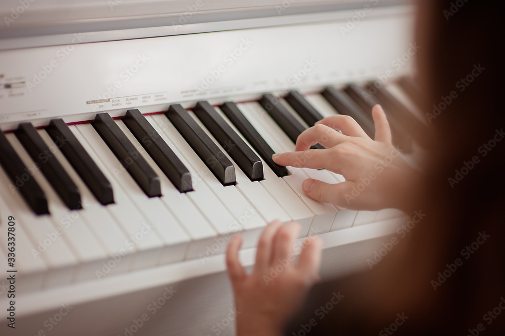 Fototapeta premium Home lesson on music for the girl on the piano. The idea of activities for the child at home during quarantine. Music concept