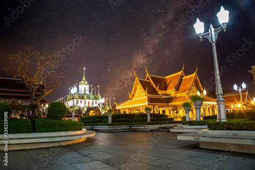 Landscape of the royal temple or Ratchanatda temple at night with starlight at Bangkok, Thailand. It is popular with both Thai and foreign tourists with milky way galaxy on the sky. photo