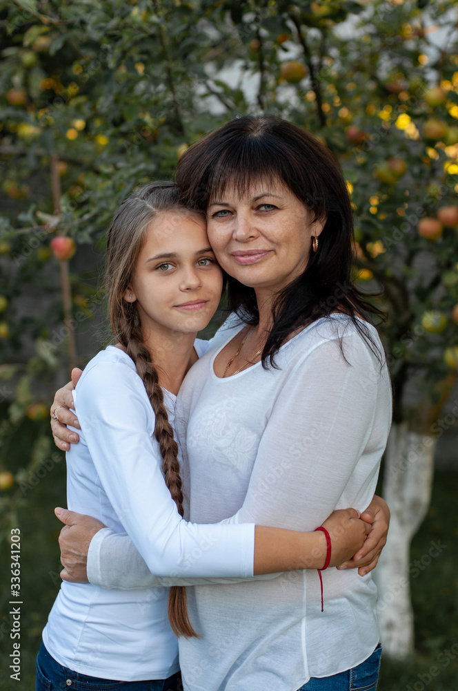 vertical close-up portrait of a beautiful fifty-year-old woman who hugs her thirteen-year-old daughter vertical close-up portrait of a beautiful fifty-year-old woman who hugs her thirteen-year-old daughter