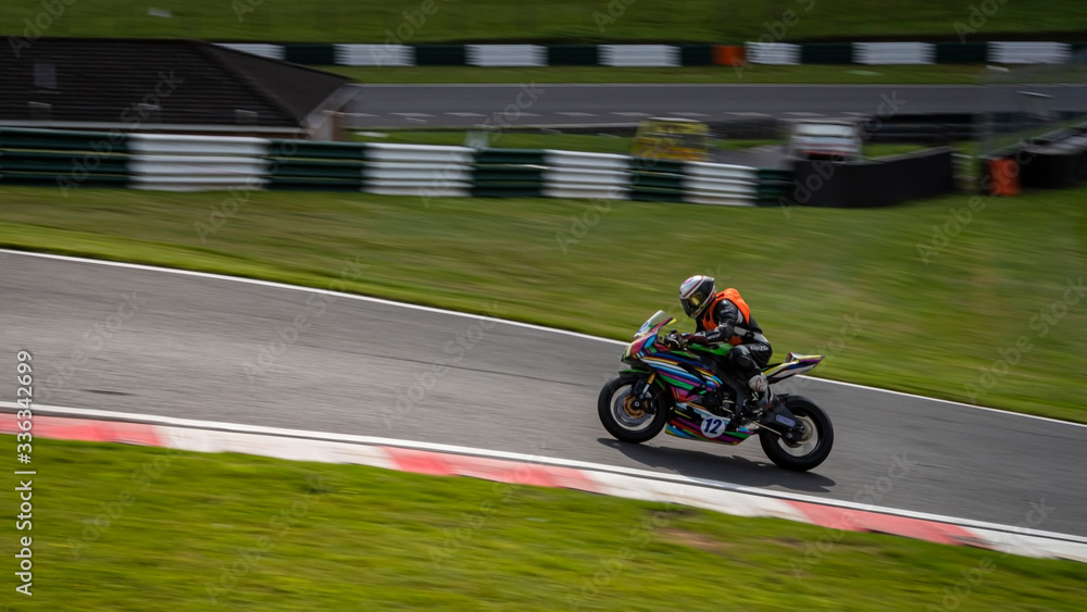 A panning image of a multicoloured racing bike passing.