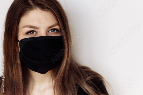 European young darkhaired woman in black medical mask on white background. Stop coronavirus.