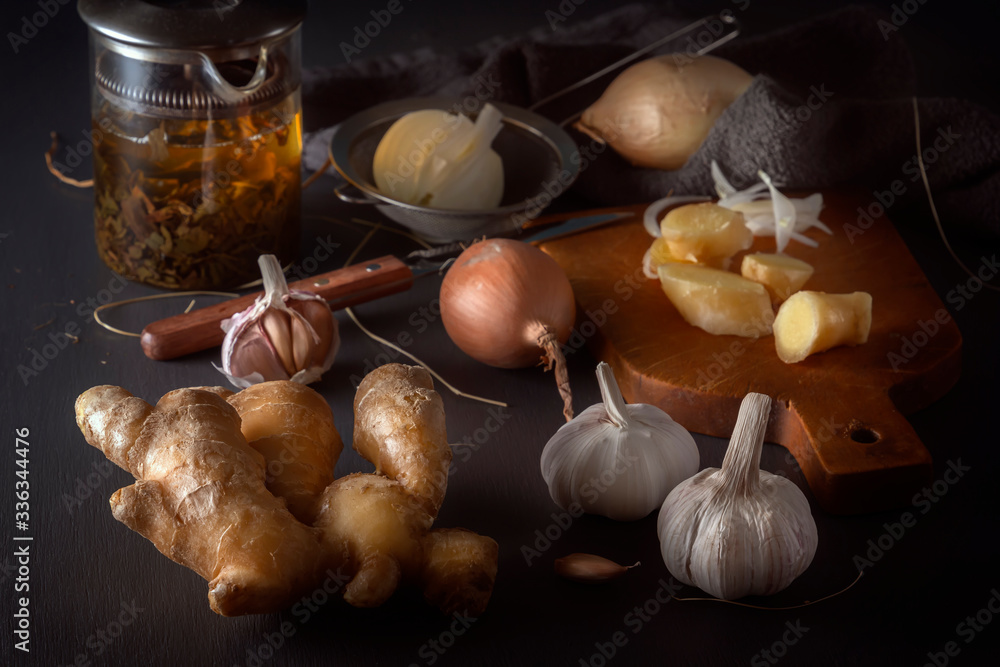 Ginger, garlic, onion - a vegetable mixture and herbal medicinal tea to increase immunity from viruses on a dark table. Low key.
