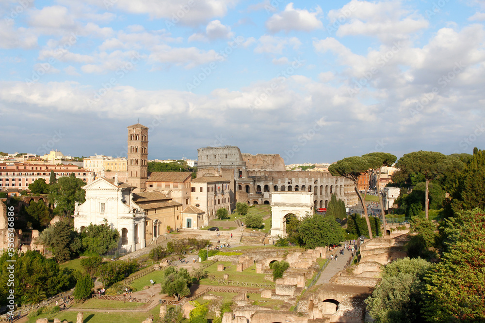 Aerial panoramic cityscape view of the Roman Forum and Roman Colosseum during sunset in Rome, Italy