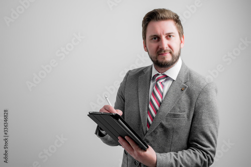 Portrait of business man wearing business clothes take notes on the tablet looking at camera