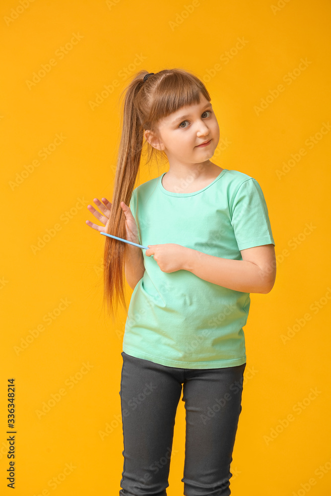 Little girl combing hair on color background Little girl combing hair on color background