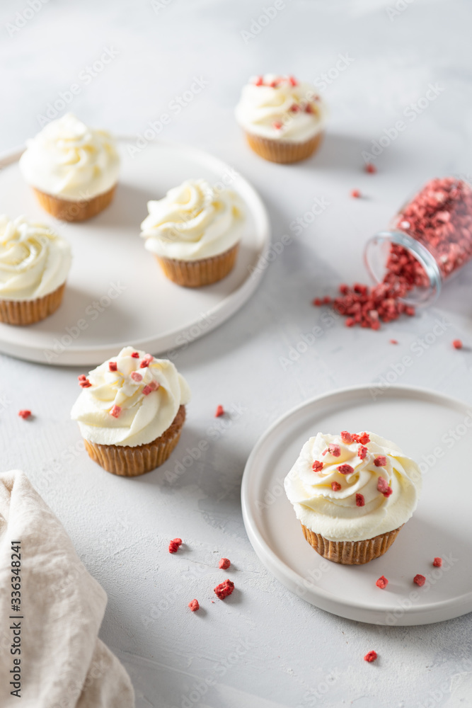 Sweet carrot cupcakes with whipped cream and dried fruits on white background. Bakery, confectionery banner, cookbook recipe, menu. Side view Sweet carrot cupcakes with whipped cream and dried fruits on white background. Bakery, confectionery banner, cookbook recipe, menu. Side view
