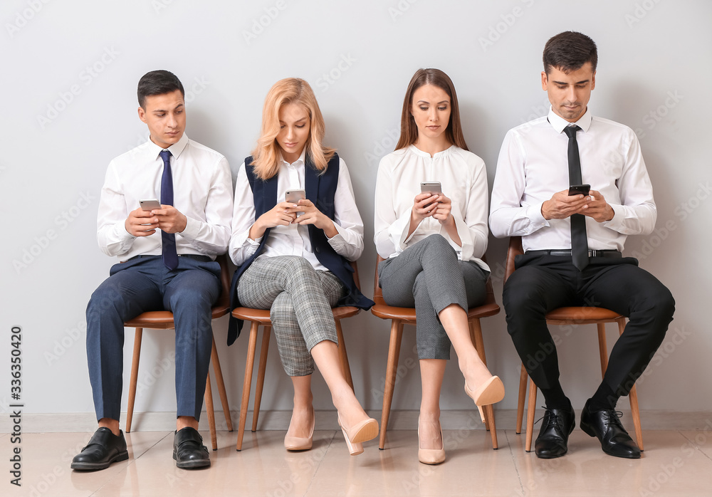 Young business people waiting in line near light wall Young business people waiting in line near light wall