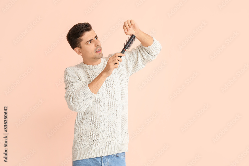 Troubled young man with hair brush on color background Troubled young man with hair brush on color background
