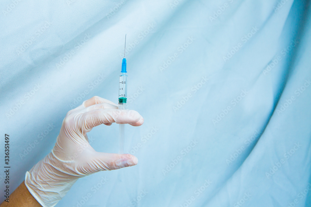 Hands in white gloves hold a syringe on a blue background. Coronavirus disinfectants, asian flu outbreak, Coronavirus 2019-nCoV, Corona virus outbreaking. Spray bottle Hands in white gloves hold a syringe on a blue background. Coronavirus disinfectants, asian flu outbreak, Coronavirus 2019-nCoV, Corona virus outbreaking. Spray bottle