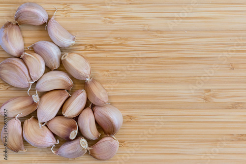 a lot of unpeeled garlic cloves on a bamboo board