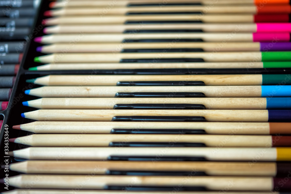 Fototapeta premium Soft focus close-up of palette of wooden colored crayons in box with plastic insert. Colored drawing pencils in a variety of colors. Close-up. Tools for painting on quarantine time. Defocused