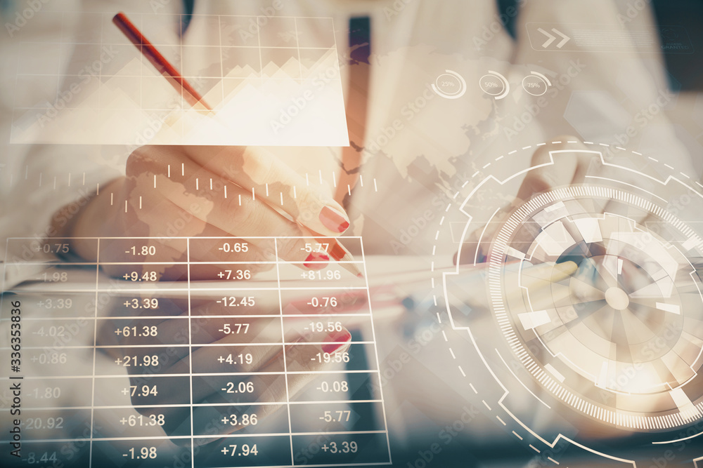 A woman hands writing information about stock market in notepad. Forex chart holograms in front. Concept of research. A woman hands writing information about stock market in notepad. Forex chart holograms in front. Concept of research.