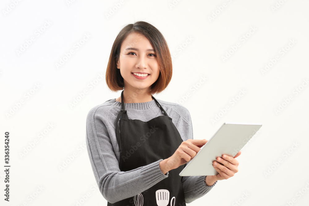 Happy small business owner in apron holding tablet standing against white background Happy small business owner in apron holding tablet standing against white background