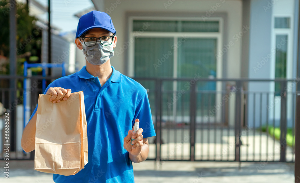 Asian Delivery man wearing mask send a food holding hand gel alcohol cleaning on front receiver shipping deliver cargo social distancing while the virus is spreading. Asian Delivery man wearing mask send a food holding hand gel alcohol cleaning on front receiver shipping deliver cargo social distancing while the virus is spreading.