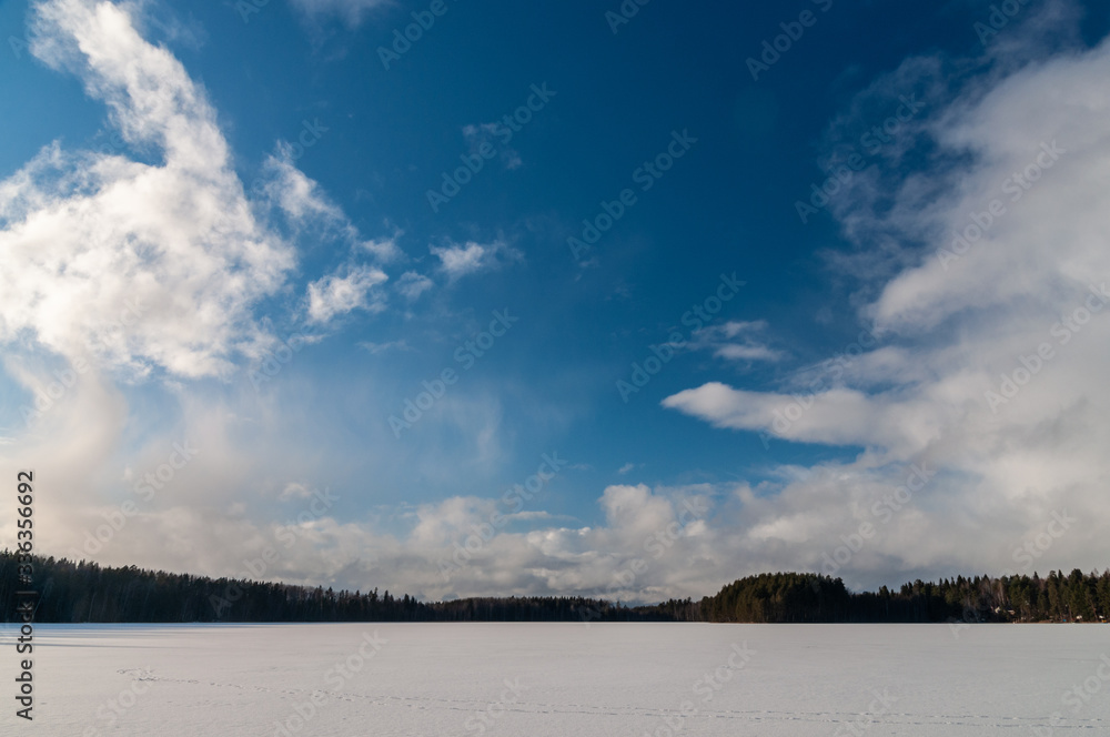 winter landscape with a frozen lake and clouds above it