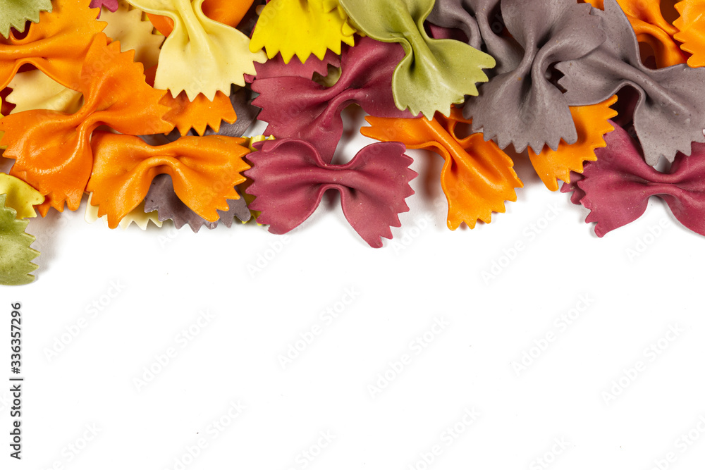 Obraz premium Italian raw multicolored farfalle pasta on white background with copy space. Colorful pasta in bow tie shape. Italian cuisine concept. Mockup for design.