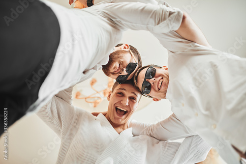 The groom is going to the wedding. Photosession of three energetic guys at the hotel. Brown tones.