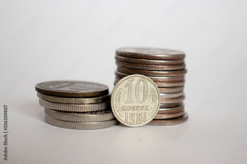 coin worth ten kopecks of the ussr stot vertically next to piled coins. coin worth ten kopecks of the ussr stot vertically next to piled coins.