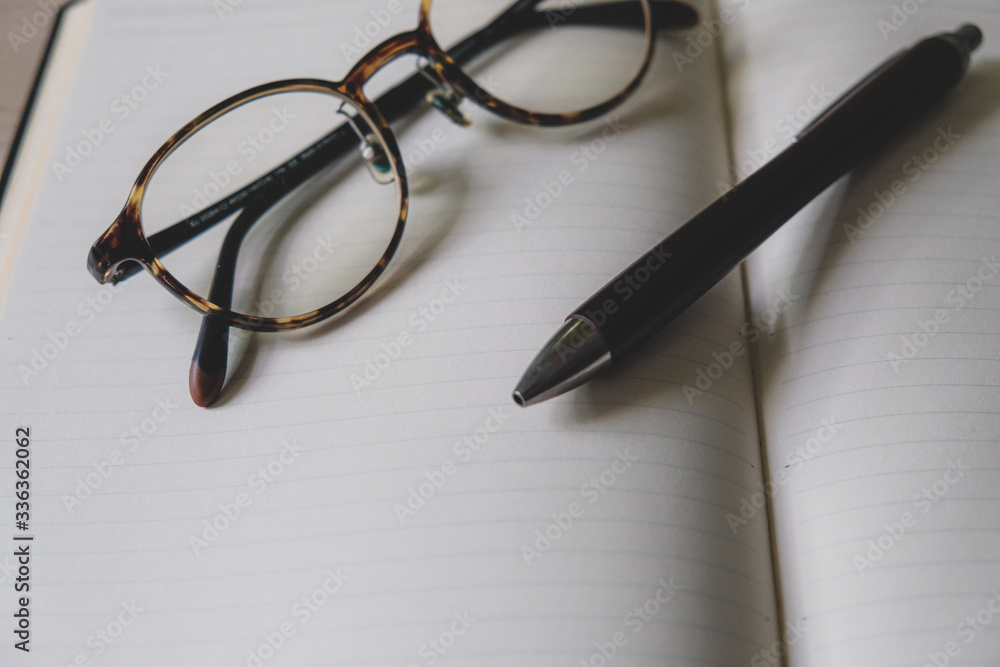 pen and glasses on notebook pen and glasses on notebook