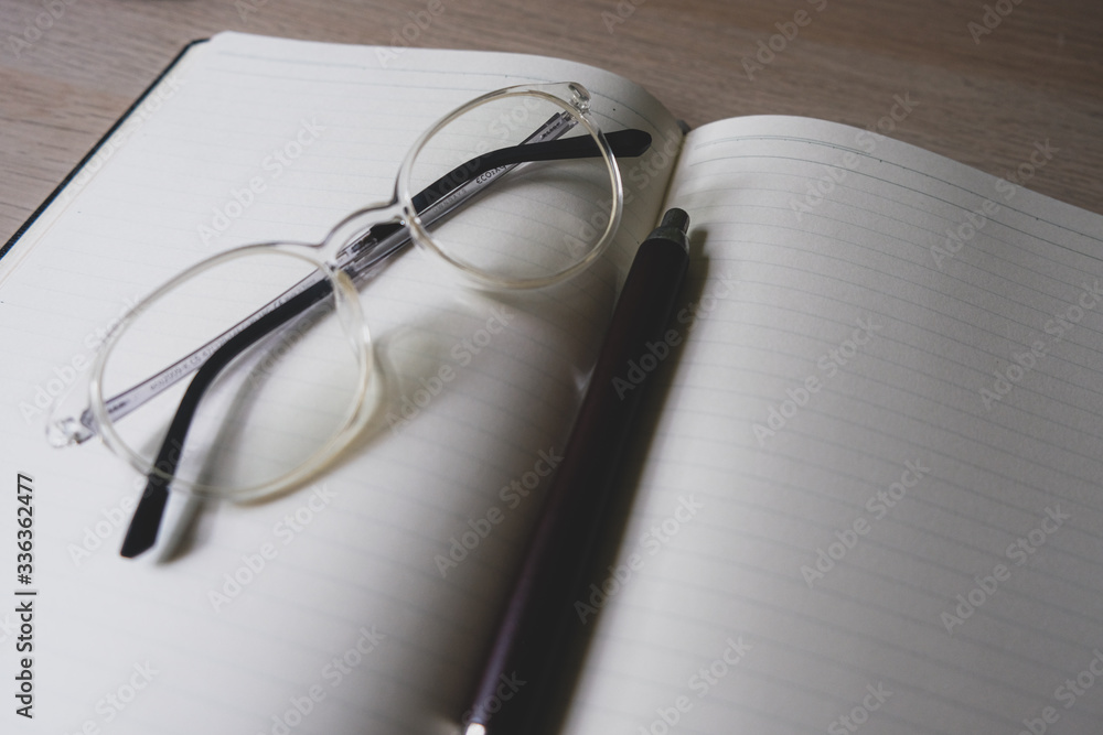 Fototapeta premium notebook and pen and glasses on the table