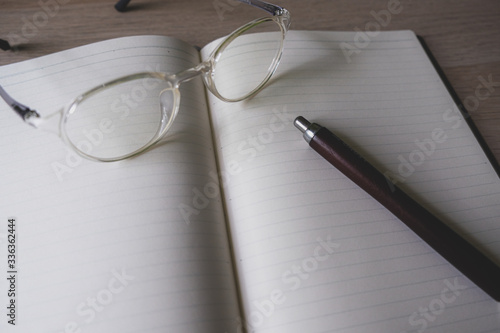 notebook and pen and glasses on the table