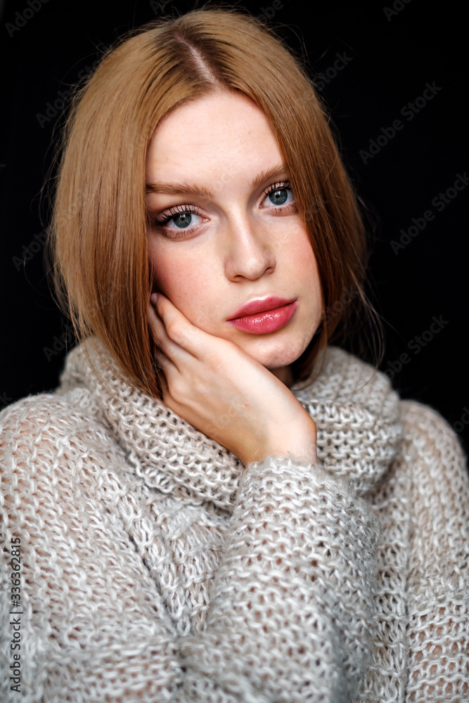 Portrait of a model girl in a sweater. young woman with brown hair posing on black background Portrait of a model girl in a sweater. young woman with brown hair posing on black background