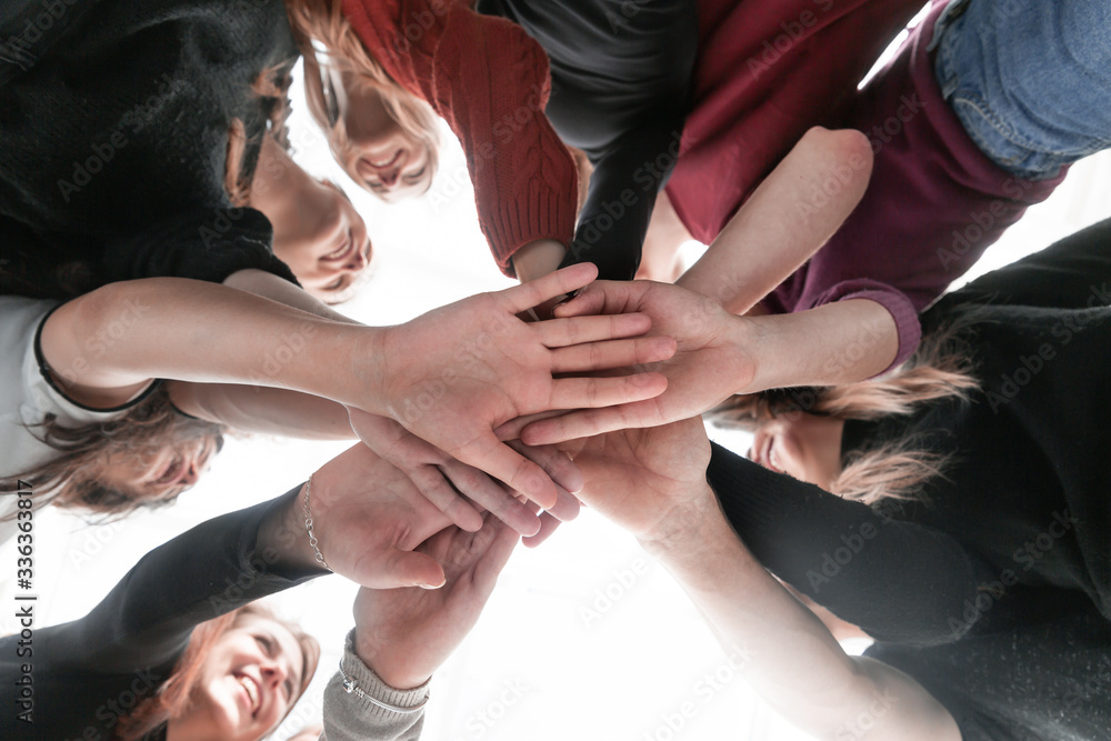 group of happy young people making a tower out of their hands