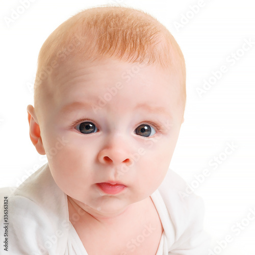 Close-up of a small 4 month old baby on a white isolate and looking at the camera. Beautiful baby eyes