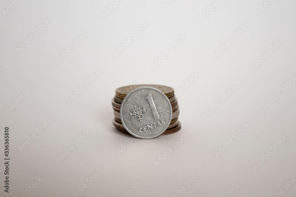 coin on a white background stands vertically next to other coins piled one on one