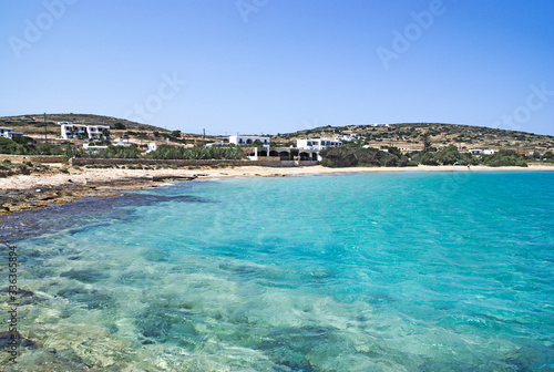 A secluded and tranquil beach on the Greek island of Koufonissi. Crystal clear blue waters at Finikas beach.. A rocky foreshore gives way to a sandy beach backed by a small taverna.